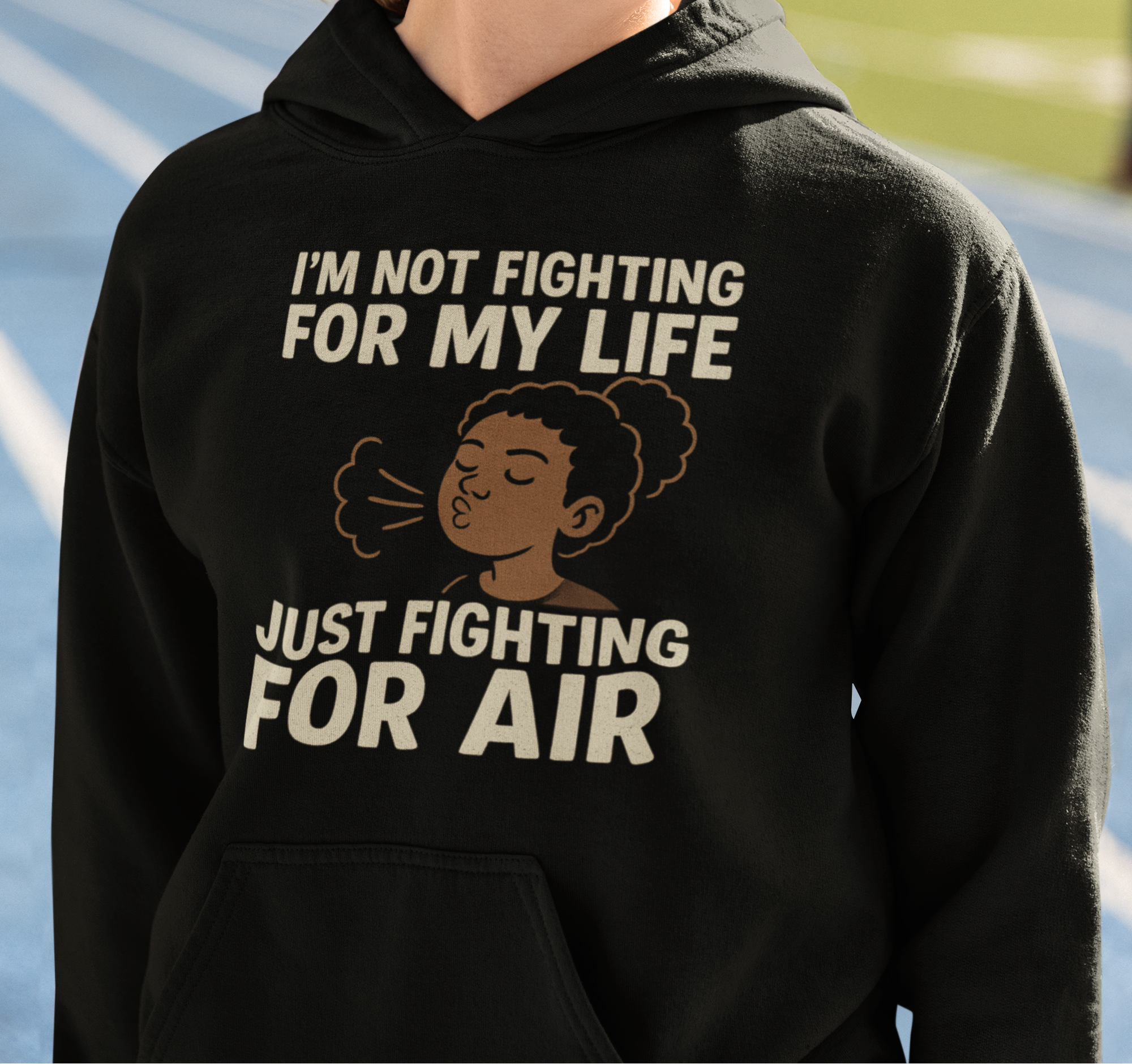 Person wearing a black hoodie with text and an illustration, standing on a track.
